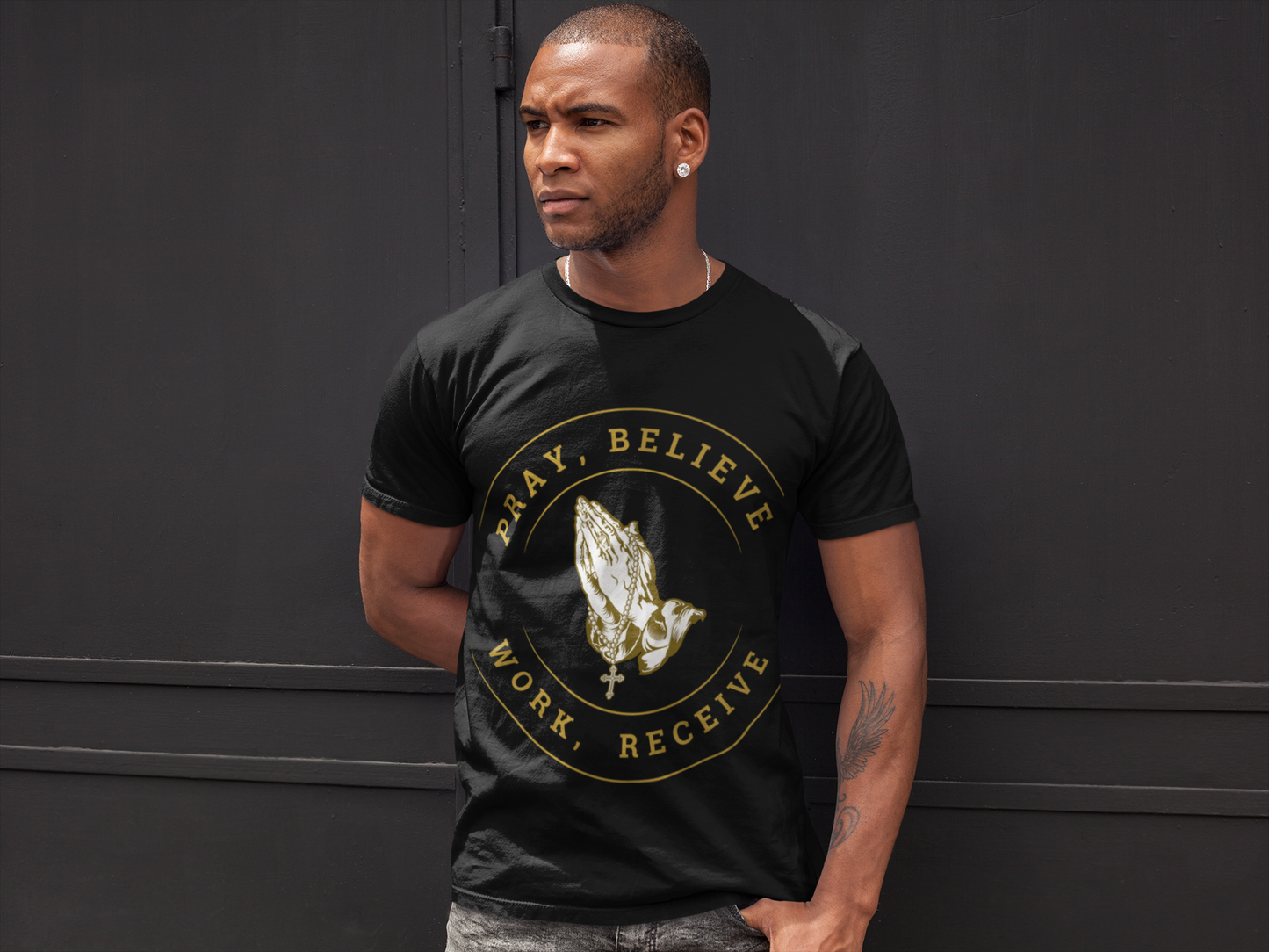 Man wearing a black t-shirt with a gold graphic and text against a dark background
